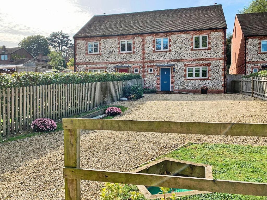 a brick house with a fence and a wooden bench at Nixey Cottage in Turville