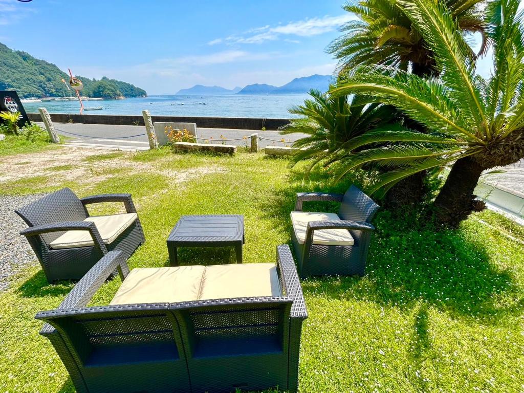 a group of chairs and tables on the grass near the water at Beach Villa Tachibana in Onomichi