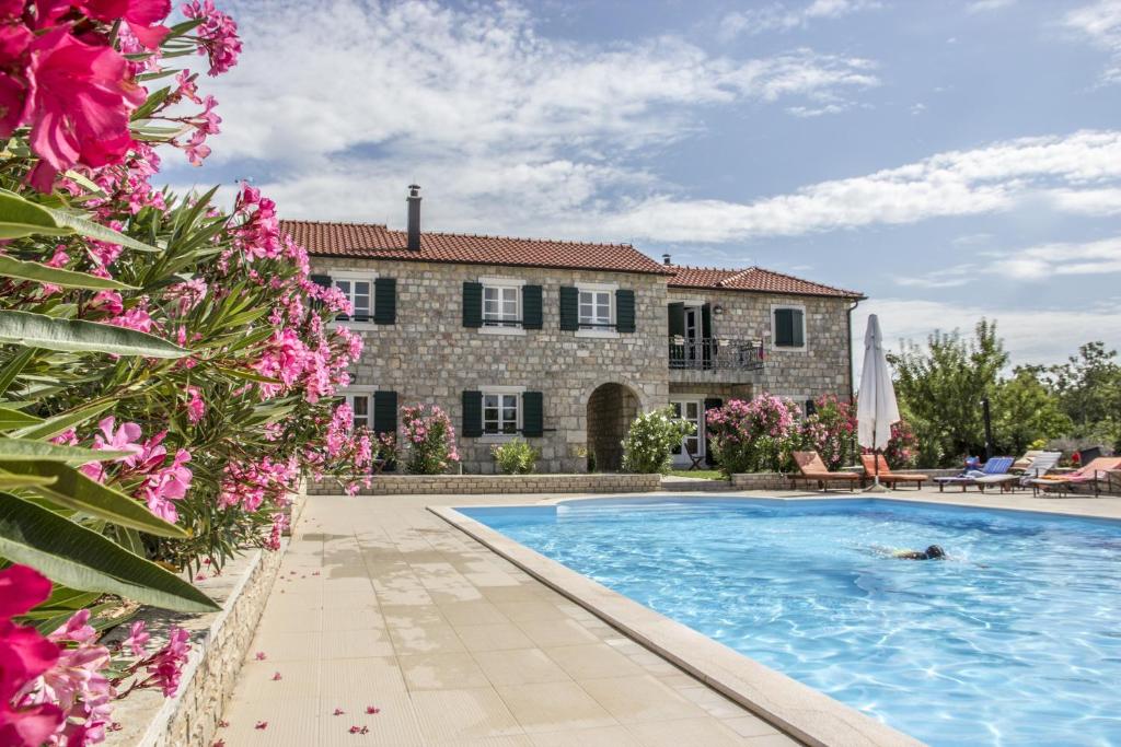 uma casa com piscina e flores rosas em Pansion Skelin em Drinovci