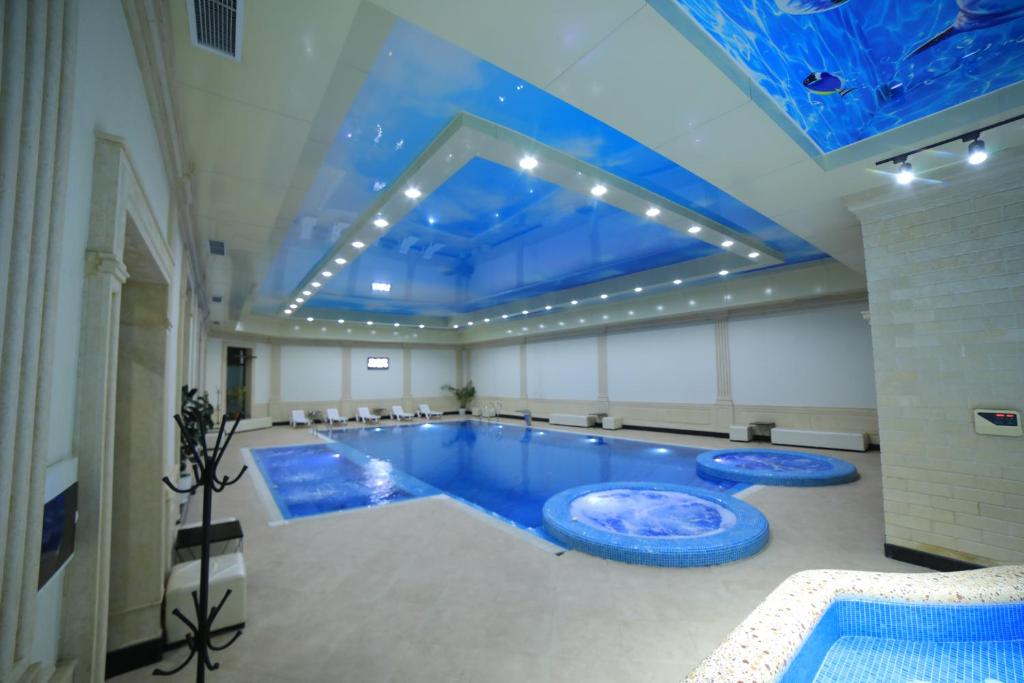 einen großen Pool mit blauer Decke in der Unterkunft Vella Elegant Hotel in Andijon