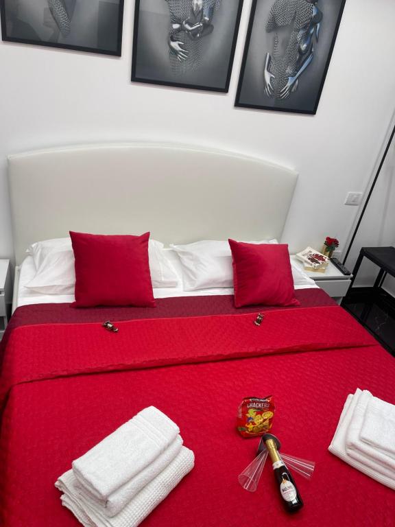 a red bed with a red blanket and towels on it at Lux House Naples Airport in Naples