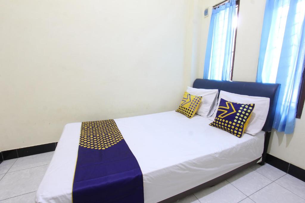 een slaapkamer met een bed met blauwe en gele kussens bij OYO Life 93157 Kos Kaloka in Tanjung