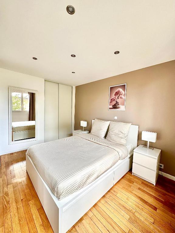 a bedroom with a large white bed and a window at Chaleureux T4, à 20 min de Paris in Argenteuil
