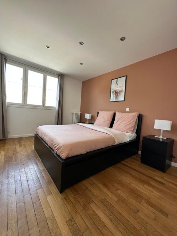 a bedroom with a large bed and two windows at Chaleureux T4, à 20 min de Paris in Argenteuil