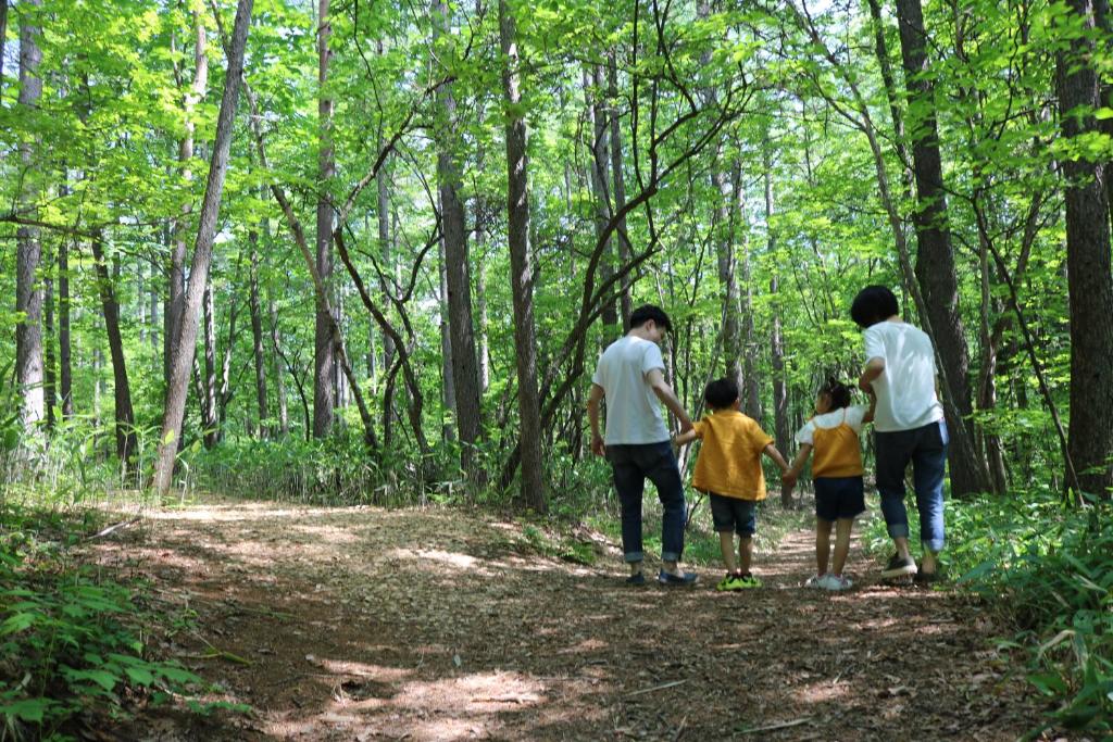 a family walking on a trail in the woods at Kusatsu Onsen Hotel Village in Kusatsu