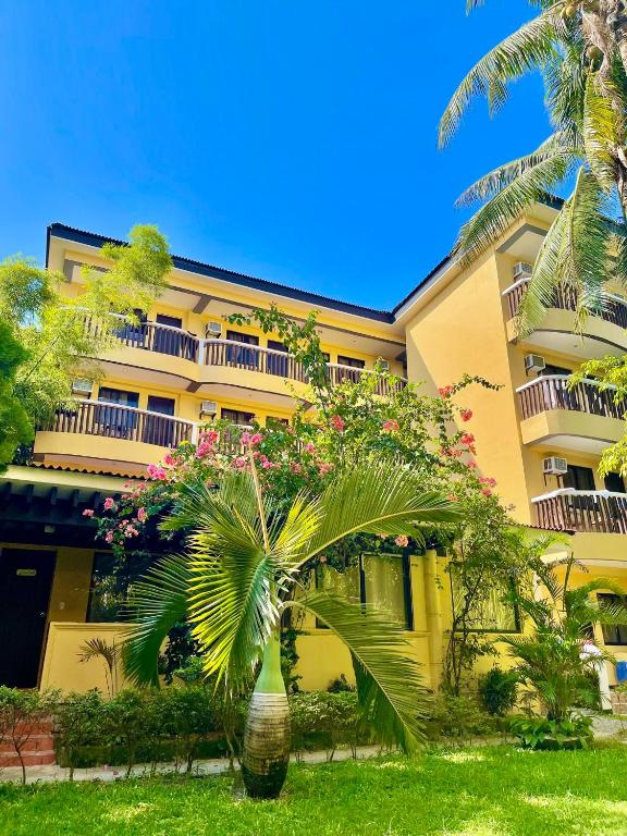 a yellow building with a palm tree in front of it at Bamboo Beach Resort & Restaurant in Boracay