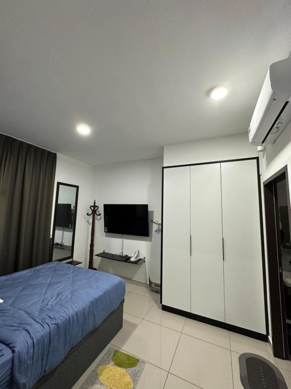 a bedroom with a bed and a flat screen tv at Desaru Dhancell Executive Homestay All Bedrooms With NETFLIX in Desaru