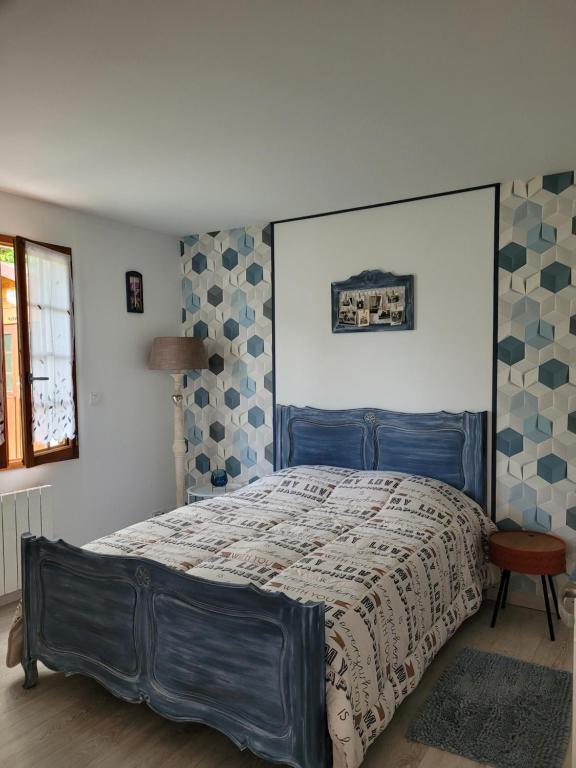 a bedroom with a bed with a blue head board at Charmante maison in Lacs