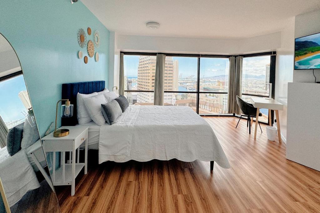 a bedroom with a large bed with a desk and windows at 1BR Ocean Sunset View With Parking in Honolulu