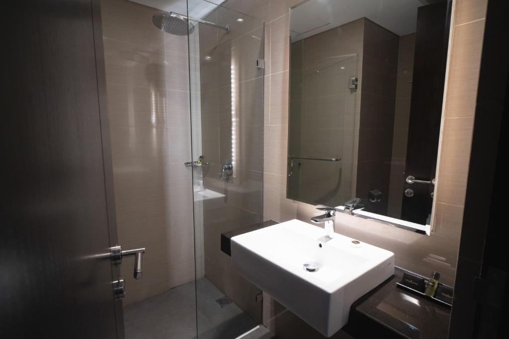 a bathroom with a sink and a glass shower at Midtown Hotel Samarinda in Samarinda