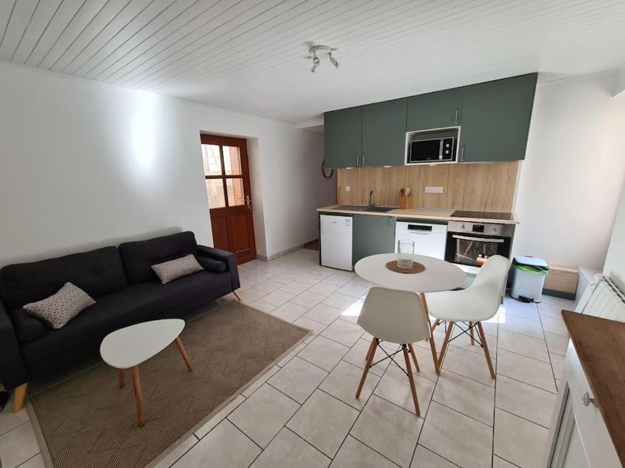 ein Wohnzimmer mit einem Sofa, einem Tisch und Stühlen in der Unterkunft Joli appartement avec coin jardin in Chalon-sur-Saône