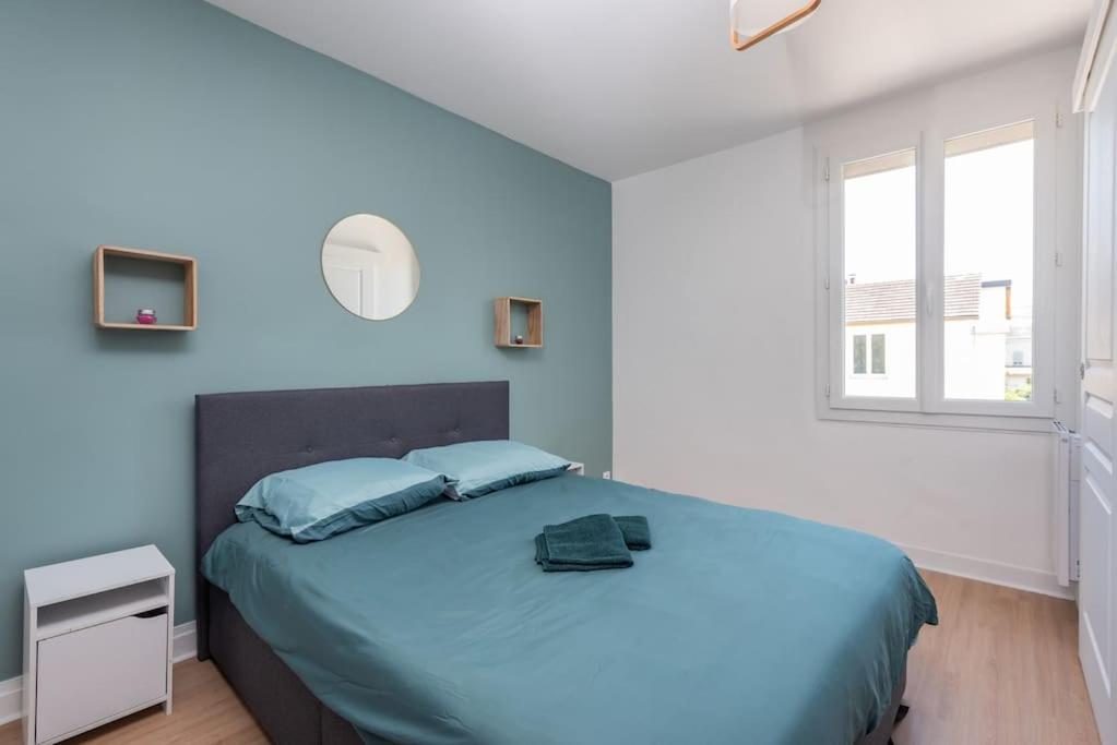 une chambre avec un lit avec des draps bleus et une fenêtre dans l'établissement Le Garden B avec salle de sport, à Rouen