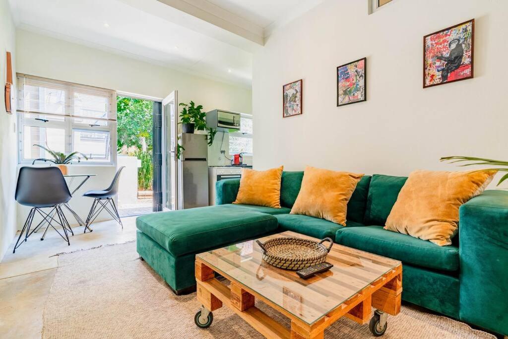 a living room with a green couch and a table at Cozy 2 bedroom garden cottage in Melville in Johannesburg