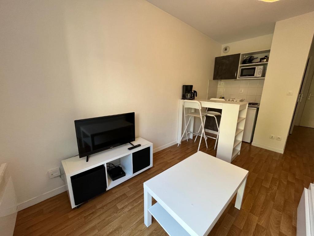 a living room with a flat screen tv and a table at Acajou, Studio avec terrasse et parking privé in Caen