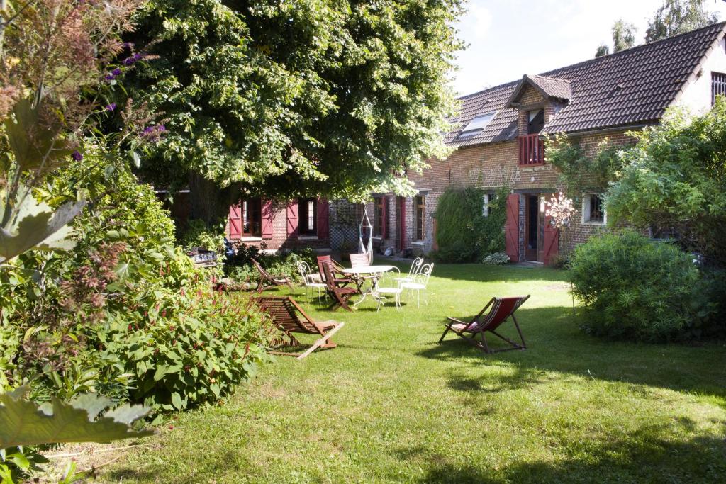 um quintal com cadeiras, uma mesa e uma casa em La ferme du tilleul em Conchy-les-Pots