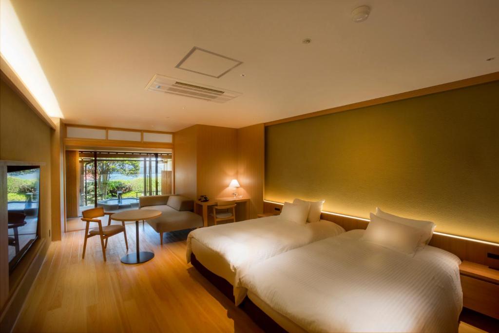 um quarto de hotel com duas camas e uma mesa em Hotel Kitanoya em Miyazu