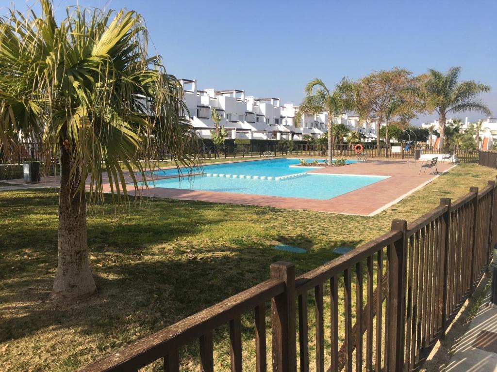 una piscina con una palmera junto a una valla en Naranjos Condado, en Alhama de Murcia