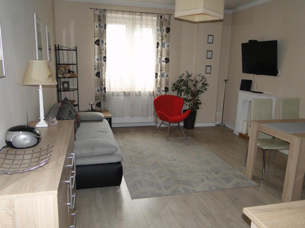 オルシュティンにあるApartament w centrum Starego Miasta 1のリビングルーム(ソファ、赤い椅子付)