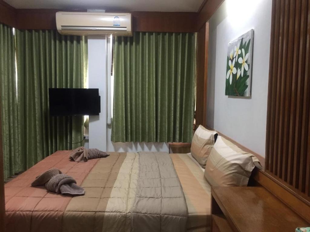 a bedroom with a large bed with green curtains at Praew Guesthouse in Phra Ae beach