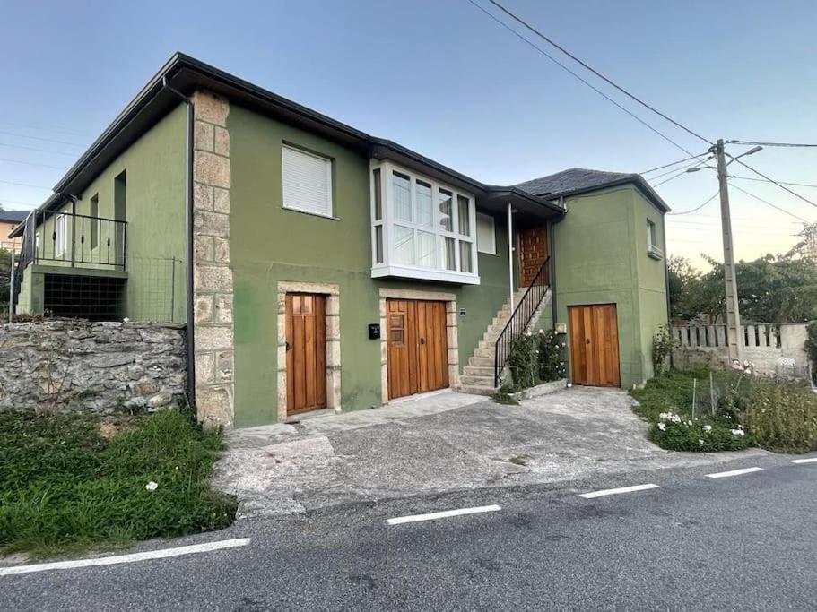 uma casa verde com portas de madeira numa rua em Casa da Baltasara em Trives