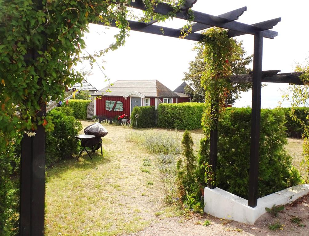 einen Garten mit einer hölzernen Pergola und einem Haus in der Unterkunft 1C, Första parkett, 50m till badstrand in Byxelkrok