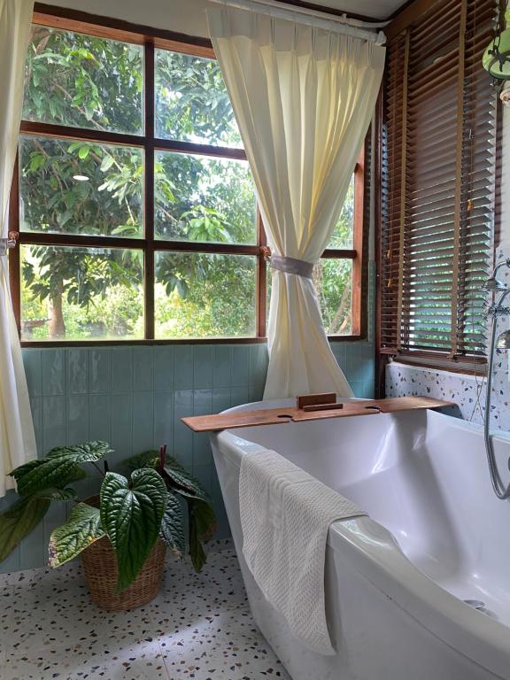 La salle de bains est pourvue d'une baignoire et d'une fenêtre. dans l'établissement Suksamer Relaxation Homestay, 