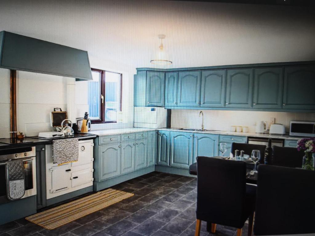 una cocina con armarios azules y una mesa. en Drainllwyn en Bala