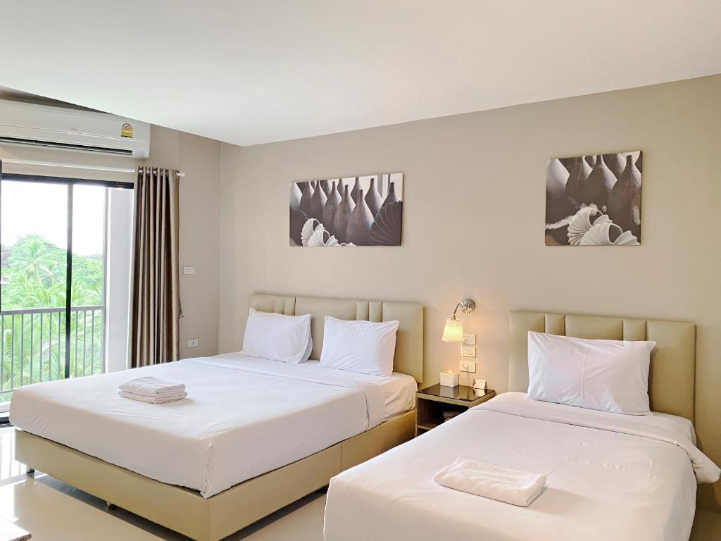 two beds in a room with a window at The Coconut Hotel in Lampang