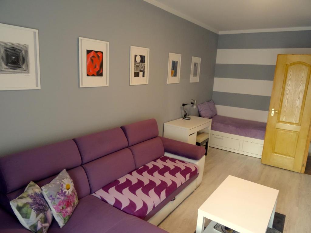 sala de estar con sofá púrpura y mesa en Árkád Apartman-Pécs, en Pécs
