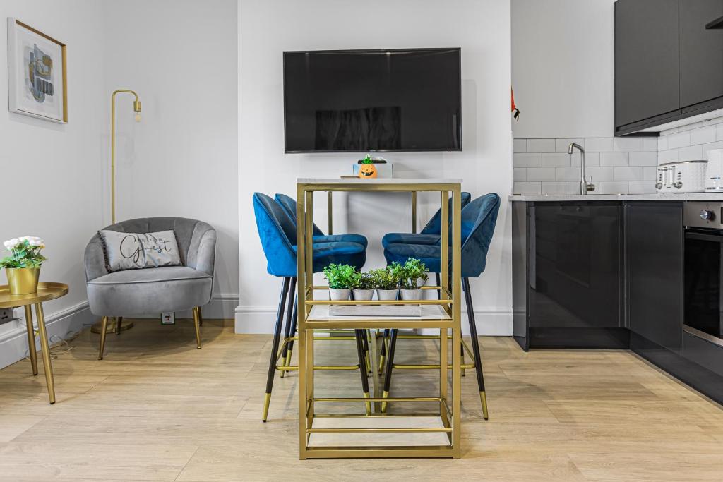 uma cozinha com cadeiras azuis e uma mesa com plantas em Modern 3 and 2 bedroom apartment in Maida Vale em Londres