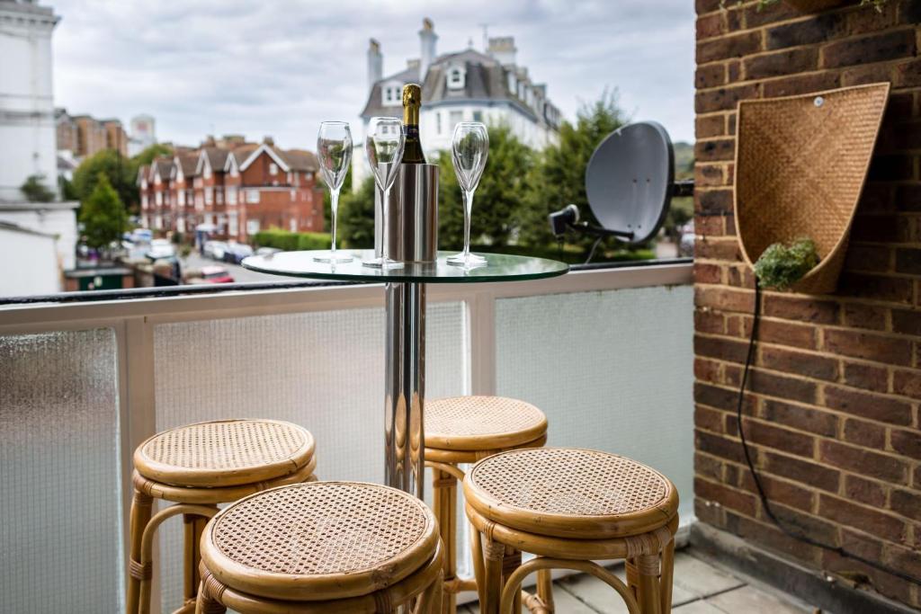 a balcony with four chairs and a table with a bottle of wine at Sea Downs - moments from beach in Eastbourne