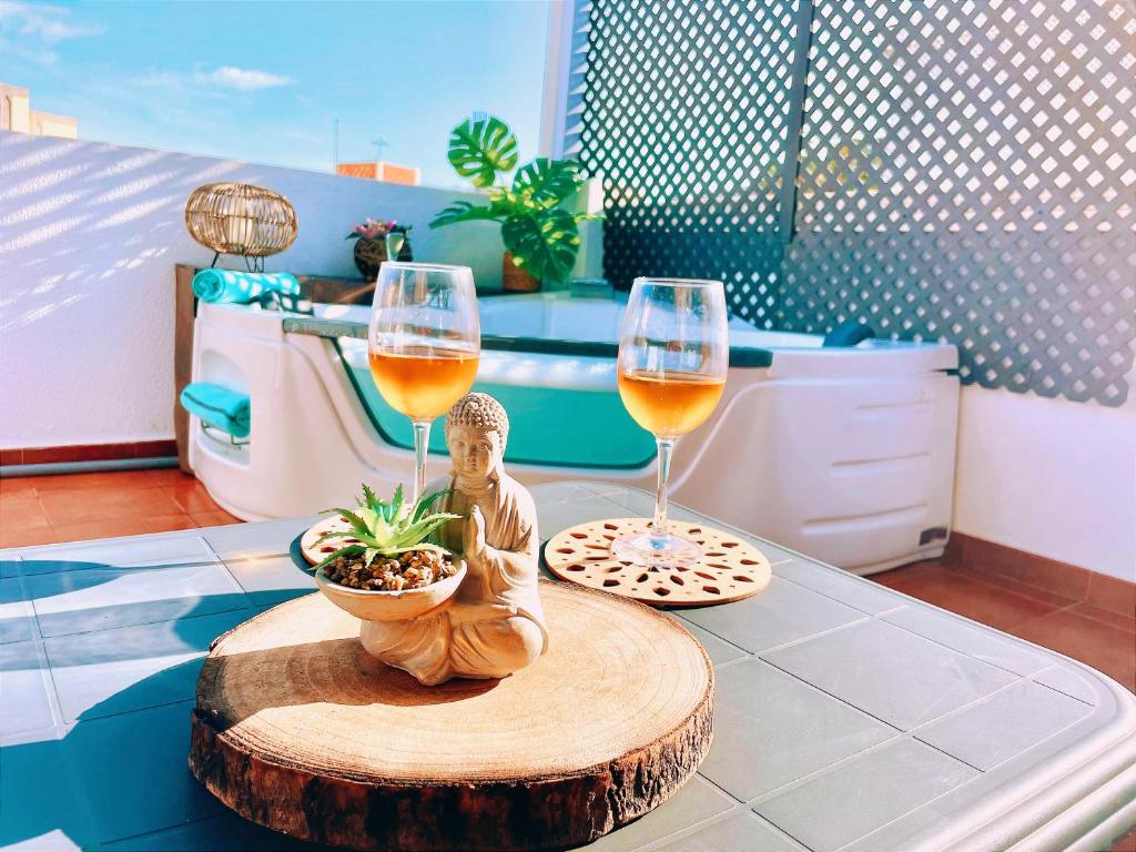 a table with two glasses of wine and a statue at Las Brisas Penthouse by SunHousesCanarias in Las Palmas de Gran Canaria