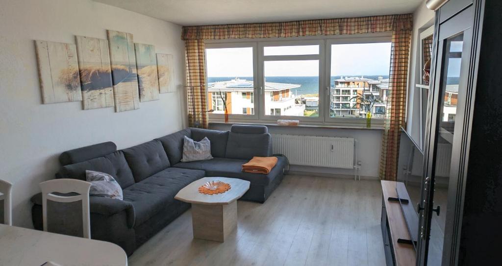 a living room with a blue couch and a table at Heiligenhafen Ostseeblick Aquamarina 57 in Heiligenhafen