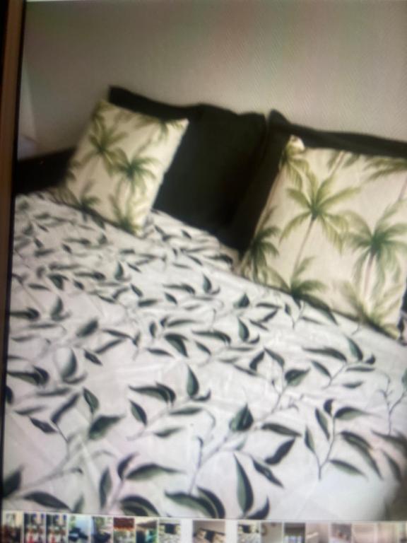 Una cama con dos almohadas con palmeras. en Studio Jeanine en Le Portel