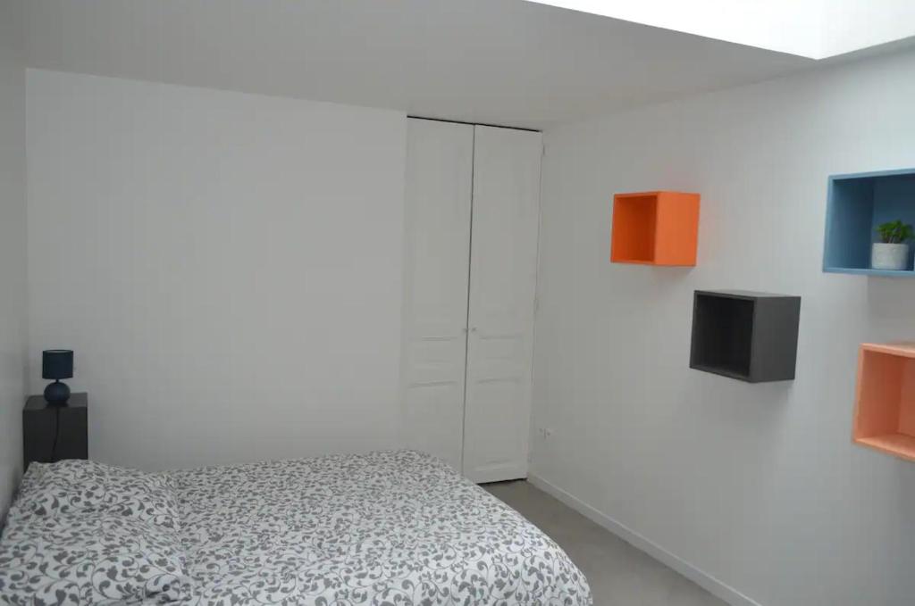 een slaapkamer met een bed en een witte muur bij Agréable maison petit jardin à 7 minutes de Reims in Pargny-lès-Reims