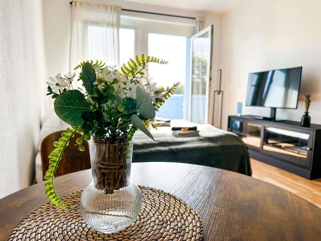 a vase of flowers on a table in a living room at Modernes Apartment Nähe Chemnitz in Neukirchen