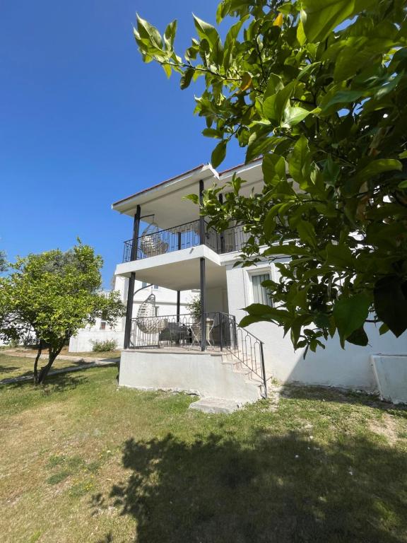 a white house with a balcony and a tree at Sun Beach Villas in Foça