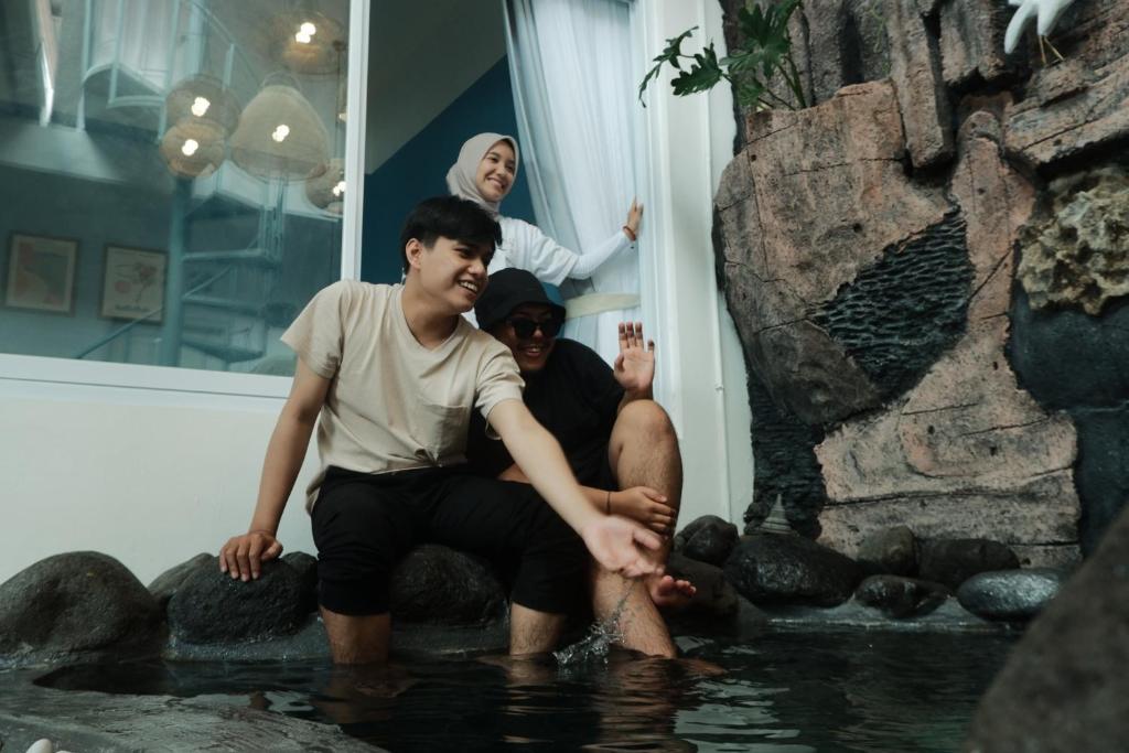 Due persone sedute in acqua con una donna di Casa Bonita: Stylish, Affordable Home & Mini Pool a Kalasan