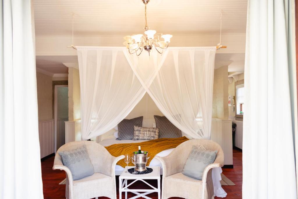 a bedroom with a bed and two chairs and a table at Anglers Court in Dullstroom