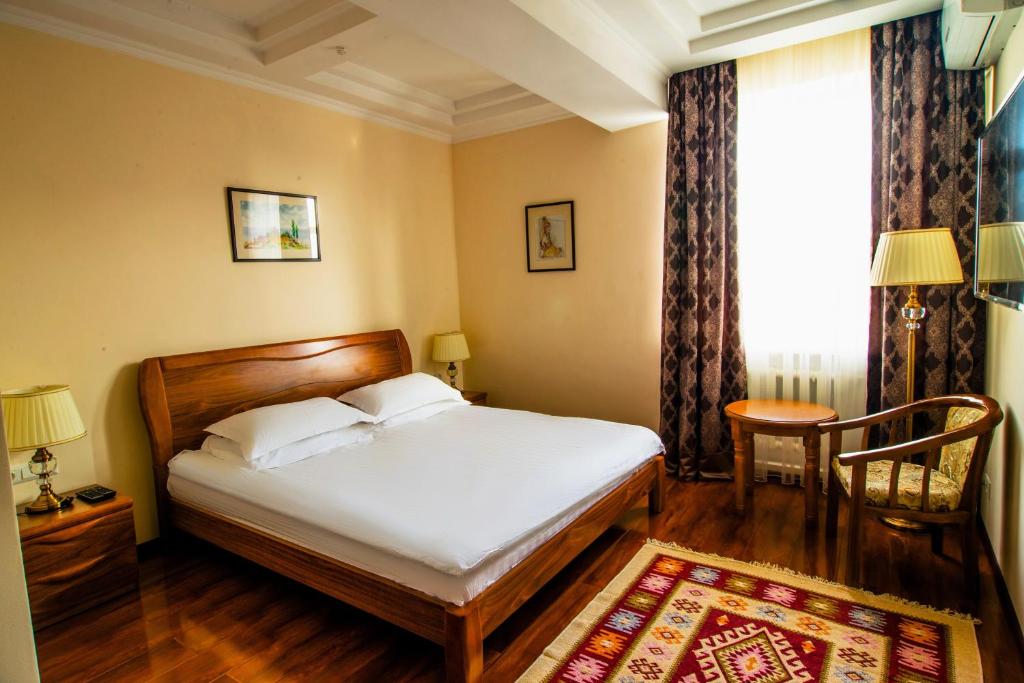 1 dormitorio con cama, mesa y ventana en Soluxe Hotel, en Bishkek
