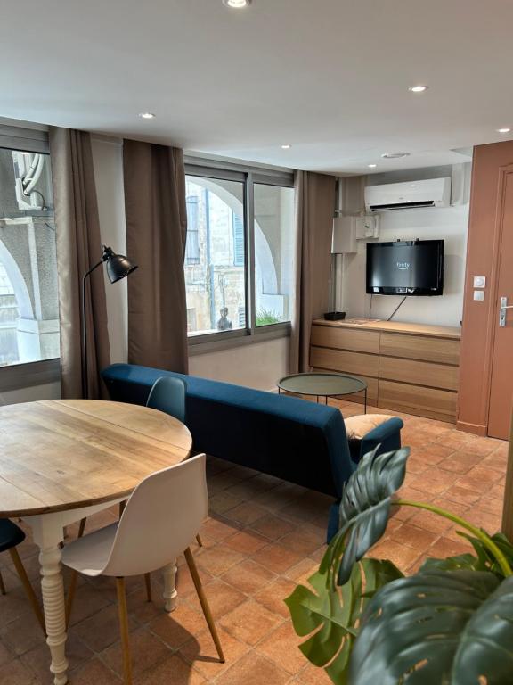 uma sala de estar com um sofá azul e uma mesa em Appartement coeur de ville -Clim, ascenseur, wifi- em Avignon