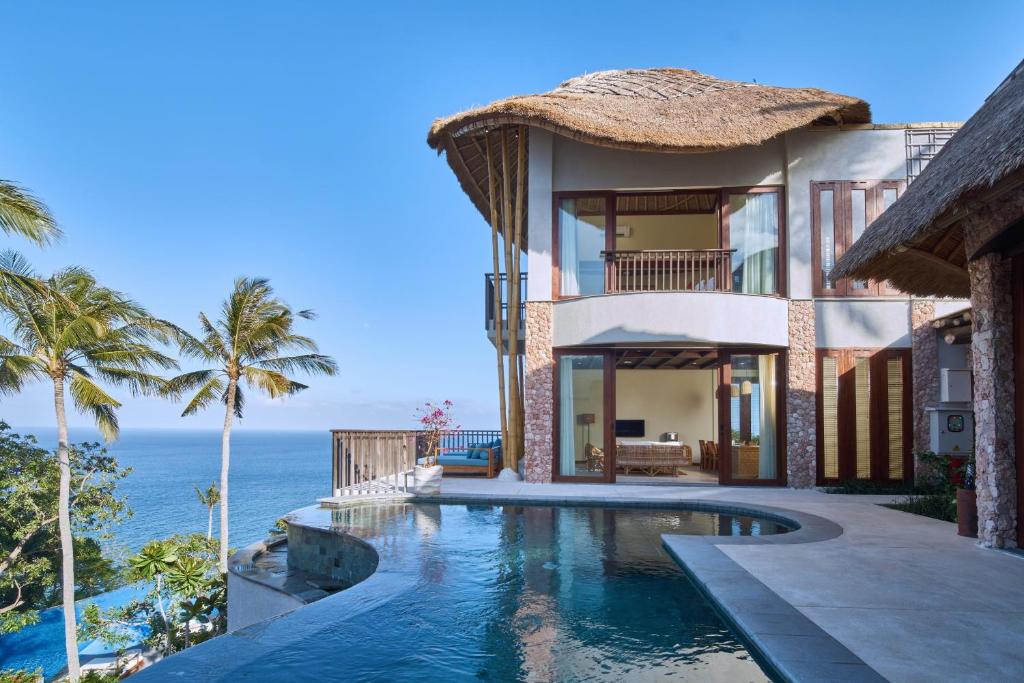 a villa with a swimming pool in front of the ocean at Kalandara Resort Lombok in Senggigi 