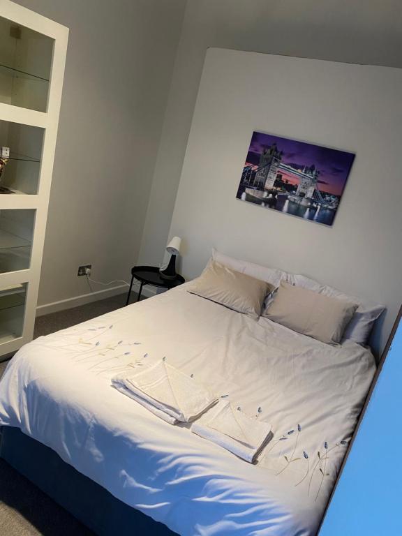 倫敦的住宿－Lovely bright double room very central，一张铺有白色床单的床和一张墙上的照片
