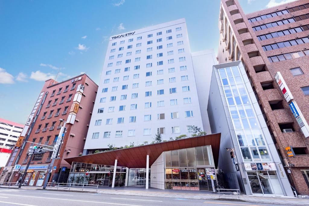 ein weißes Gebäude in einer Stadtstraße mit Gebäuden in der Unterkunft Tokyu Stay Fukuoka Tenjin in Fukuoka