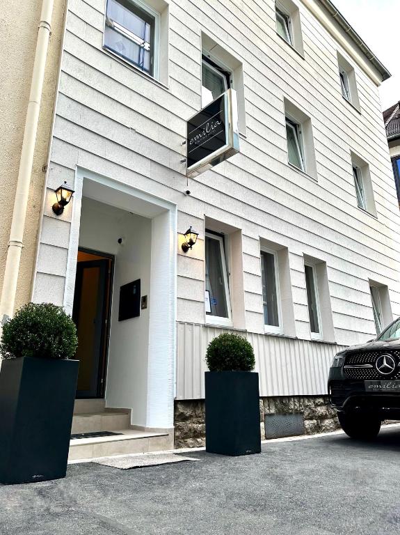 a white building with two plants in front of it at Hotel Emilia in Würzburg