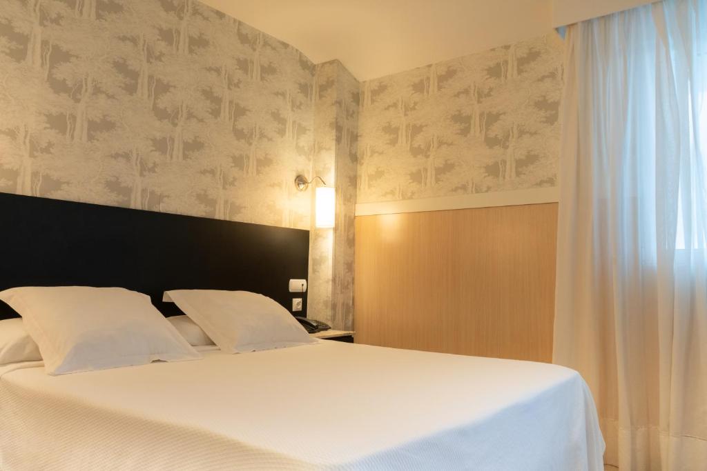 a bedroom with a white bed and a window at Hotel Don Diego in Suances