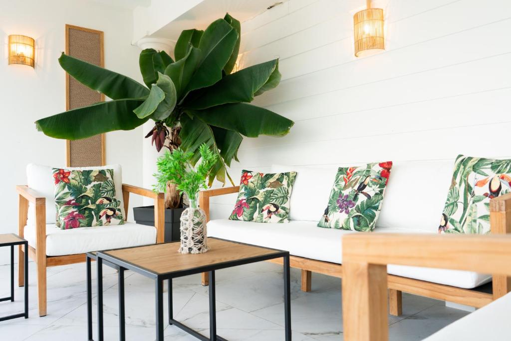 a living room with white furniture and a potted plant at Hotel Don Diego in Suances