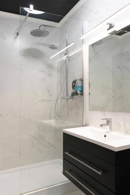 a bathroom with a sink and a shower with a mirror at Hotel Don Diego in Suances