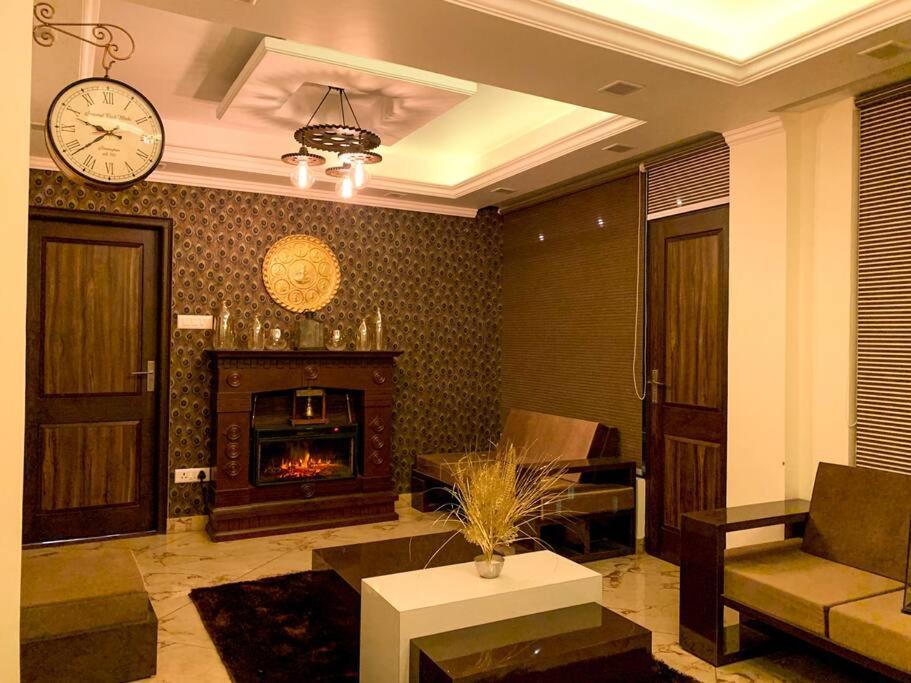 a living room with a fireplace and a clock on the wall at Uptown Boutique Home - 2BHK with drive-in in Shimla