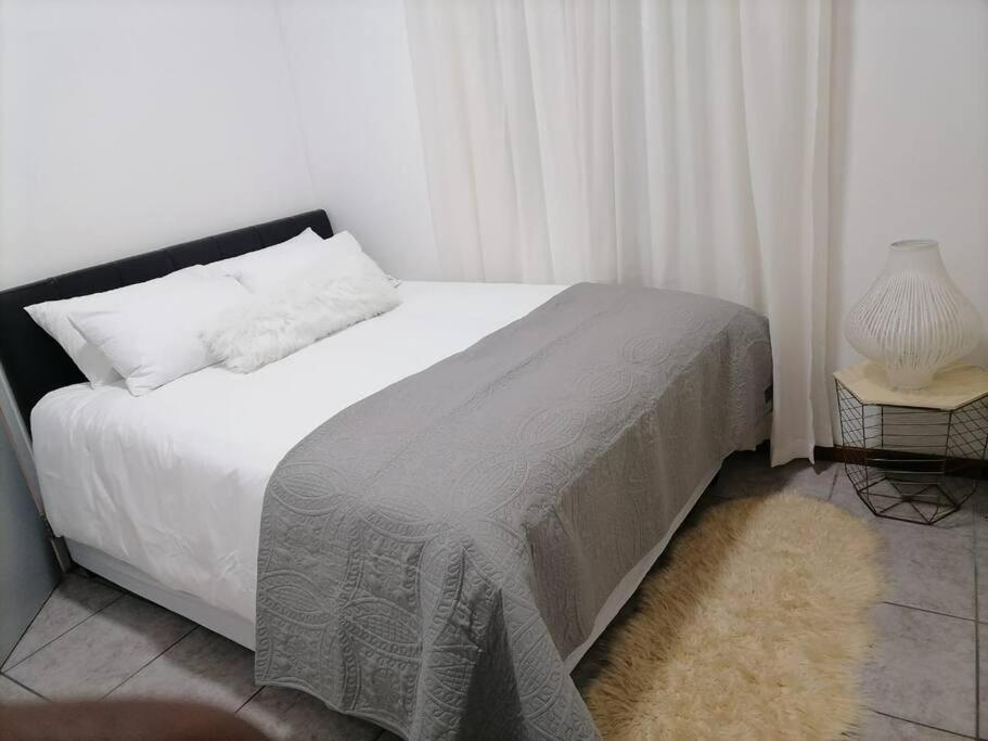 1 dormitorio con cama blanca y cabecero negro en Two bedroom flatlet in Panorama, en Ciudad del Cabo